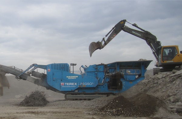 Seitenansicht eines Prallbrecher Pegson Terex XH250 der von einen Bagger beladen wird