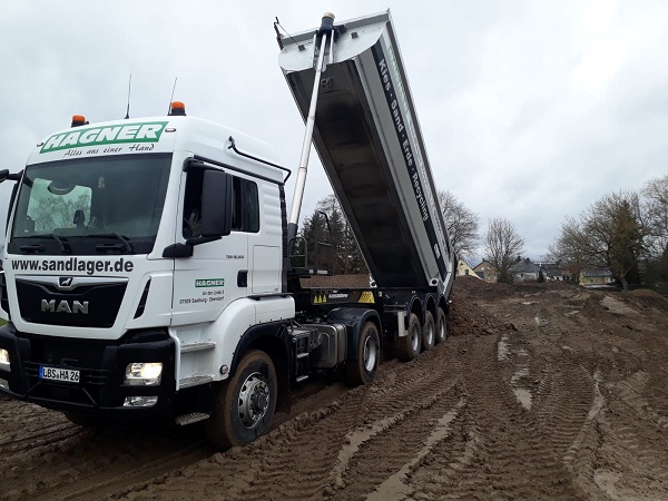 Seiteansicht einer MAN TGS 18.440 Sattelzugmaschine mit Tieflader und Bagger als Ladung der Hagner Industrieservice Baustoffrecycling e.K.